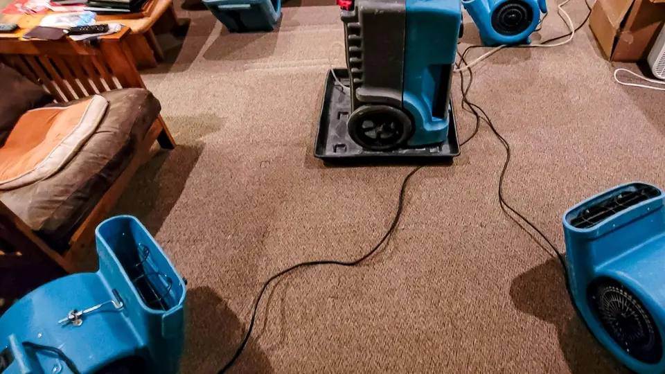 Dehumidifier and air movers drying a carpeted living room