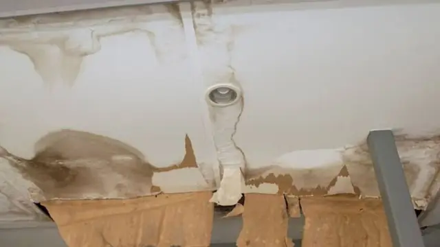Stained and sagging ceiling around a light fixture after a leak